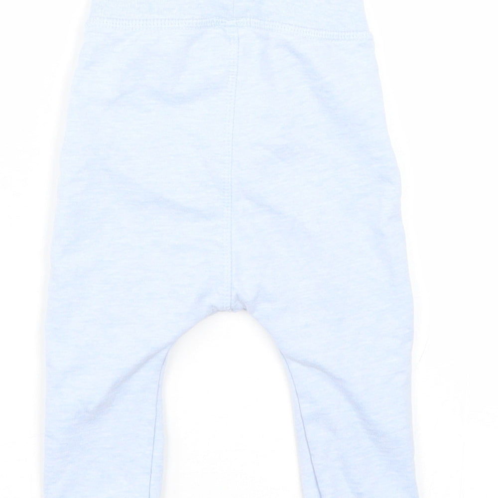 Brand and care label for Nutmeg girls’ blue sweatpants, size 6-9, months
