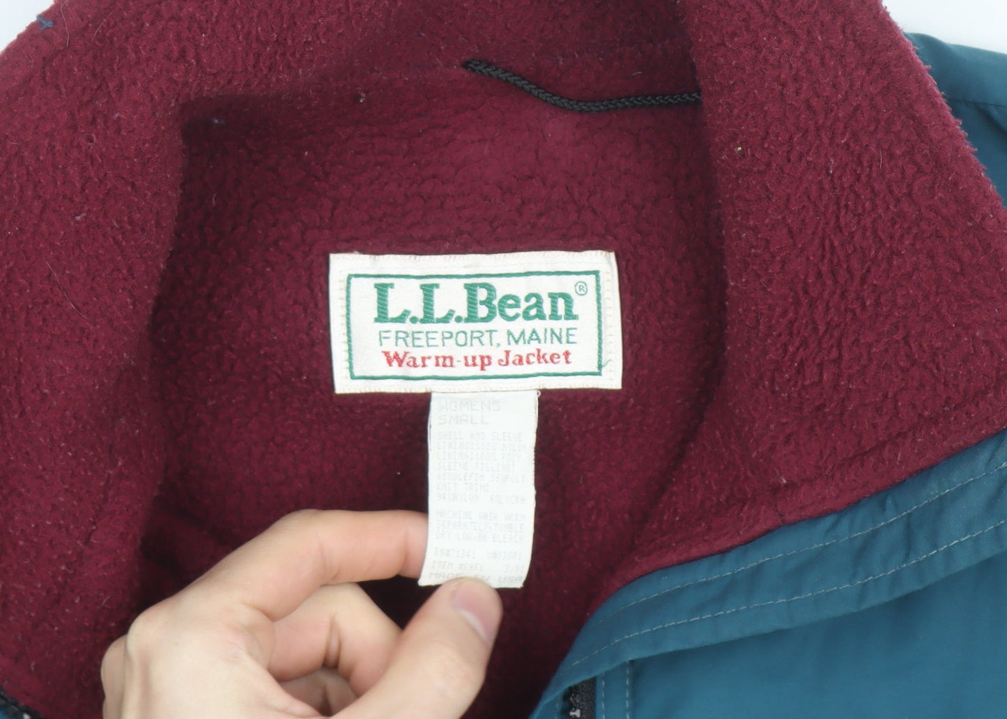 Brand and care label for L.L.Bean women’s blue warm-up nylon fleece-lined windproof jacket, size S