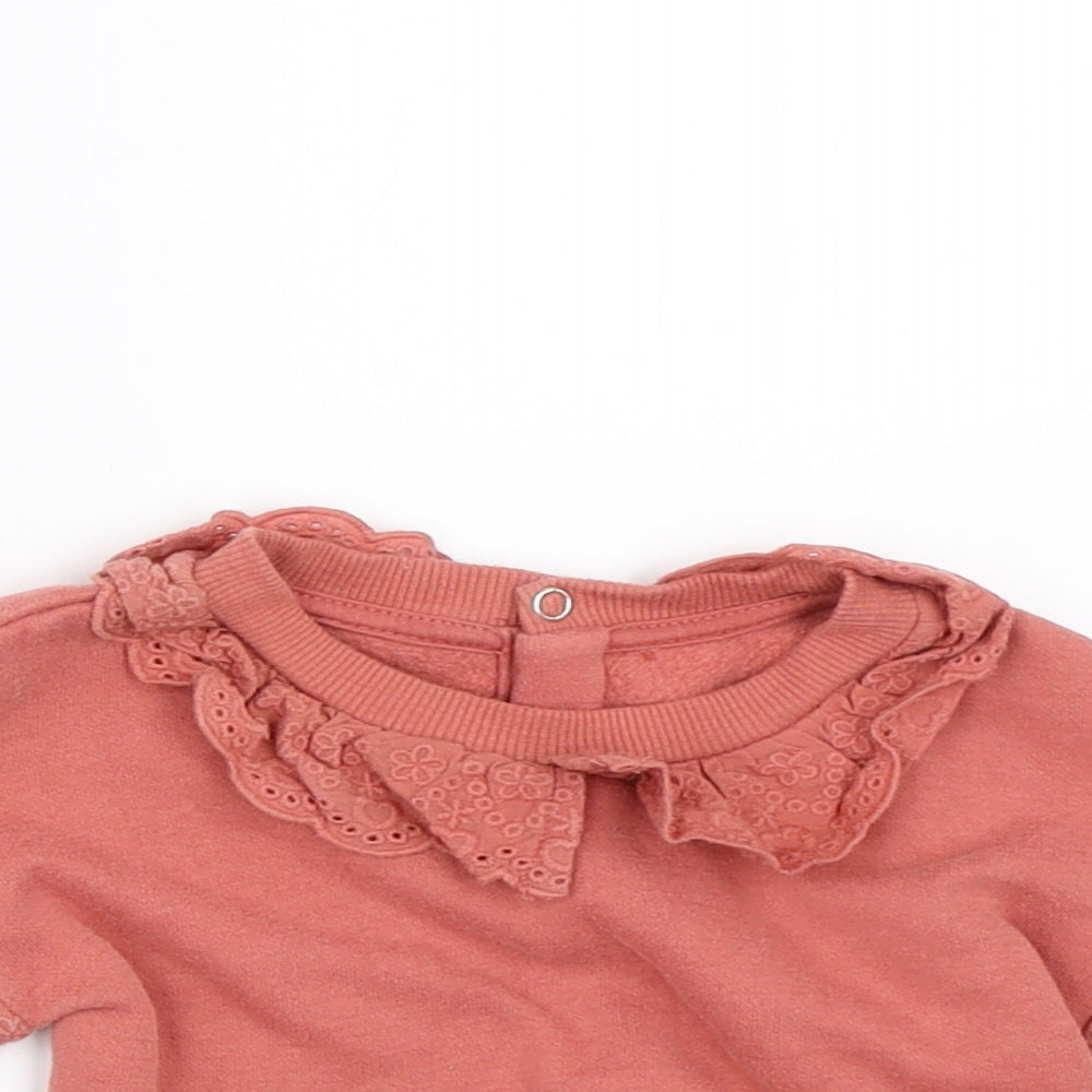 Close-up detail of Primark girls’ orange jumper, size 6-9, months