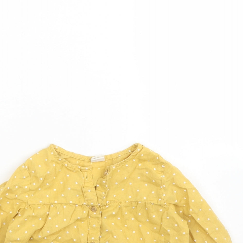 Close-up detail of H&M girls’ yellow polka dot cotton basic button-up, size 2, years round neck button